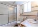 Bright bathroom featuring a shower-tub combo, frosted glass enclosure, and a vanity with ample lighting at 2700 S Holly St # 115, Denver, CO 80222