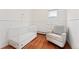 Bedroom featuring a crib and glider chair, plus wood floors, and a white-paneled accent wall at 5123 Milwaukee St, Denver, CO 80216