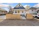 Charming home featuring a yellow front door, and a stylish wooden fence in front of the yard at 5123 Milwaukee St, Denver, CO 80216