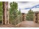 Outdoor deck with stone columns, wood decking, and a scenic view of trees and greenery at 4965 Huntwick Pl, Highlands Ranch, CO 80130