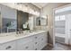 Modern bathroom vanity featuring double sinks, large mirrors, and a view of the bathtub shower combination at 2067 E Phillips Pl, Centennial, CO 80122