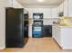 Bright kitchen featuring white cabinets, tile floors, and modern black appliances creating a clean and functional space at 585 S Alton Way # 6B, Denver, CO 80247