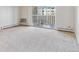 An empty living room showing a balcony entrance with lattice-style design and radiator heaters at 585 S Alton Way # 6B, Denver, CO 80247