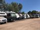 RV Storage lot with multiple RVs parked in an outdoor storage area with trees in the background at 585 S Alton Way # 6B, Denver, CO 80247