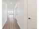 Long hallway featuring hardwood floors, white walls, and an opening to a bright living space at 1904 Water Birch Way, Castle Rock, CO 80108