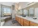 Light-filled bathroom with a double vanity, soaking tub, and glass block at 881 Kirby Ct, Watkins, CO 80137