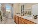 Well-lit bathroom with double sinks, wood cabinets, large mirrors and a window at 881 Kirby Ct, Watkins, CO 80137