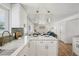 Bright kitchen with white cabinetry and island with seating, quartz countertops and stainless steel sink at 6068 Lee St, Arvada, CO 80004