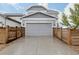 A two-car garage with a concrete driveway and wooden fence in front of a modern house with gray siding and stone accents at 640 E Fremont Pl, Littleton, CO 80122