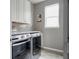 Modern laundry room with gray tile, white cabinets, subway tile backsplash, and new front-loading washer and dryer at 640 E Fremont Pl, Littleton, CO 80122