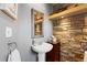 Powder room with stone accent wall, pedestal sink and elegant mirror at 7841 Deertrail Dr, Parker, CO 80138