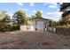 View of three-car garage with light colored doors and a large gravel parking area surrounded by mature trees at 7841 Deertrail Dr, Parker, CO 80138