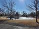 Community pond view in winter from parking lot with clear sky and bare trees at 57 Scott S, Broomfield, CO 80020