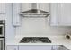 Features a stainless steel vent hood, modern cooktop, and gray cabinets at 7380 S Shady Grove Way, Aurora, CO 80016
