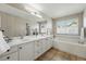 Bathroom features double sinks with large mirror, window with soaking tub and tile floor at 2252 S Yosemite Cir, Denver, CO 80231