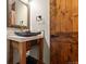 Stylish powder room featuring a vessel sink and custom wood cabinetry at 7113 Echo Hills Club Rd, Larkspur, CO 80118