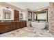 Bathroom featuring double vanities, a soaking tub, and stone floors at 7113 Echo Hills Club Rd, Larkspur, CO 80118
