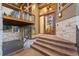 Elegant entrance featuring a wooden door, stone accents, and a covered porch, enhancing curb appeal at 7113 Echo Hills Club Rd, Larkspur, CO 80118