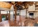 Spacious living room featuring exposed beams, stone fireplace, hardwood floors, and scenic views at 7113 Echo Hills Club Rd, Larkspur, CO 80118