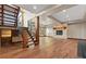 Open-concept living room with wood floors, stone fireplace, and custom staircase with metal railings at 7113 Echo Hills Club Rd, Larkspur, CO 80118