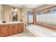 A spacious bathroom with a soaking tub, wooden cabinets, and a large mirror at 2411 S Garfield St, Denver, CO 80210