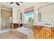 Bright bathroom showcasing a soaking tub, glass shower, and dual sinks with wood cabinetry at 14958 Wistera Way, Broomfield, CO 80023