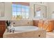 Bright bathroom features a soaking tub with tile surround and a large window for natural light at 14958 Wistera Way, Broomfield, CO 80023