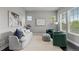 Bright living room featuring a comfortable couch, two green chairs, and large windows with natural light at 23252 E Glidden Dr, Aurora, CO 80016