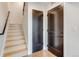 Bright condo hallway with wood floors, two dark doors, and wooden stairs at 2400 S Delaware St # 1, Denver, CO 80223