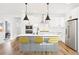Modern kitchen features white cabinets, stainless steel appliances, pendant lights, and a large island with seating at 5984 Fulton St, Denver, CO 80238