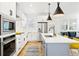 Bright, open kitchen with stainless appliances, large island with seating, and sleek white cabinetry at 5984 Fulton St, Denver, CO 80238