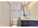Bathroom with a white tile shower and a dark vanity with a single sink at 14074 Yellow Tip Dr, Parker, CO 80134