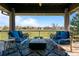 An inviting covered patio with comfortable seating and a fire pit, overlooking a lush green space at 9099 E Harvard Ave, Denver, CO 80231