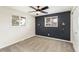 Cozy bedroom featuring a dark accent wall, neutral carpet, two windows, and modern lighting fixtures at 6614 Everett St, Arvada, CO 80004