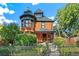 Charming Victorian home with a turret, covered porch, and wrought iron fence, surrounded by lush landscaping at 3015 Lowell Blvd, Denver, CO 80211