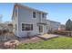 A light blue two-story home featuring a green lawn, brick fire pit, and a brown wooden fence in the backyard at 20521 E Bellewood Pl, Aurora, CO 80015