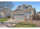 Two-story home with gray siding, brick accents, and a two-car garage, set against a clear blue sky at 20521 E Bellewood Pl, Aurora, CO 80015