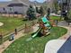 Spacious backyard featuring a playground, green lawn, and wooden fence at 23579 E Swallow Cir, Aurora, CO 80016