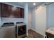 Well-equipped laundry room with modern washer and dryer, storage cabinets, and a sliding barn door at 23579 E Swallow Cir, Aurora, CO 80016