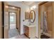 Neutral bathroom with a single sink vanity and framed oval mirror, adjoining the shower and neighboring room at 9188 W Ontario Dr, Littleton, CO 80128