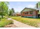A beautiful shot of a brick home with green trim surrounded by healthy green grass on a sunny day at 4945 Perry St, Denver, CO 80212