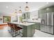 Bright and modern kitchen featuring a stainless steel refrigerator, kitchen island, and green cabinetry at 4945 Perry St, Denver, CO 80212