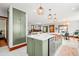 Spacious kitchen island featuring green cabinets, a marble countertop, and views into the living room at 4945 Perry St, Denver, CO 80212