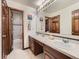 Bathroom features double sinks, white tile floors, and dark wood cabinets with a door to a shower at 19748 E Pinewood Dr, Aurora, CO 80016