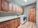 Functional laundry room with wood cabinets, a sink, and a modern washing machine and dryer at 19748 E Pinewood Dr, Aurora, CO 80016