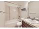 Bathroom with white tiled shower/tub, single vanity, and large mirror at 1945 Basil St, Strasburg, CO 80136