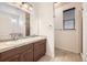 Bathroom featuring double sinks, large mirror, tiled floors, shower, and ample vanity storage at 1945 Basil St, Strasburg, CO 80136