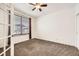 Bedroom featuring neutral carpeting, large window with blinds, and an open doorway at 1945 Basil St, Strasburg, CO 80136