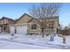 Home exterior with a three-car garage and landscaping, pictured in a snowy, winter setting at 1945 Basil St, Strasburg, CO 80136