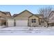 Exterior view of a home with a three-car garage, showcasing the facade in a winter setting at 1945 Basil St, Strasburg, CO 80136